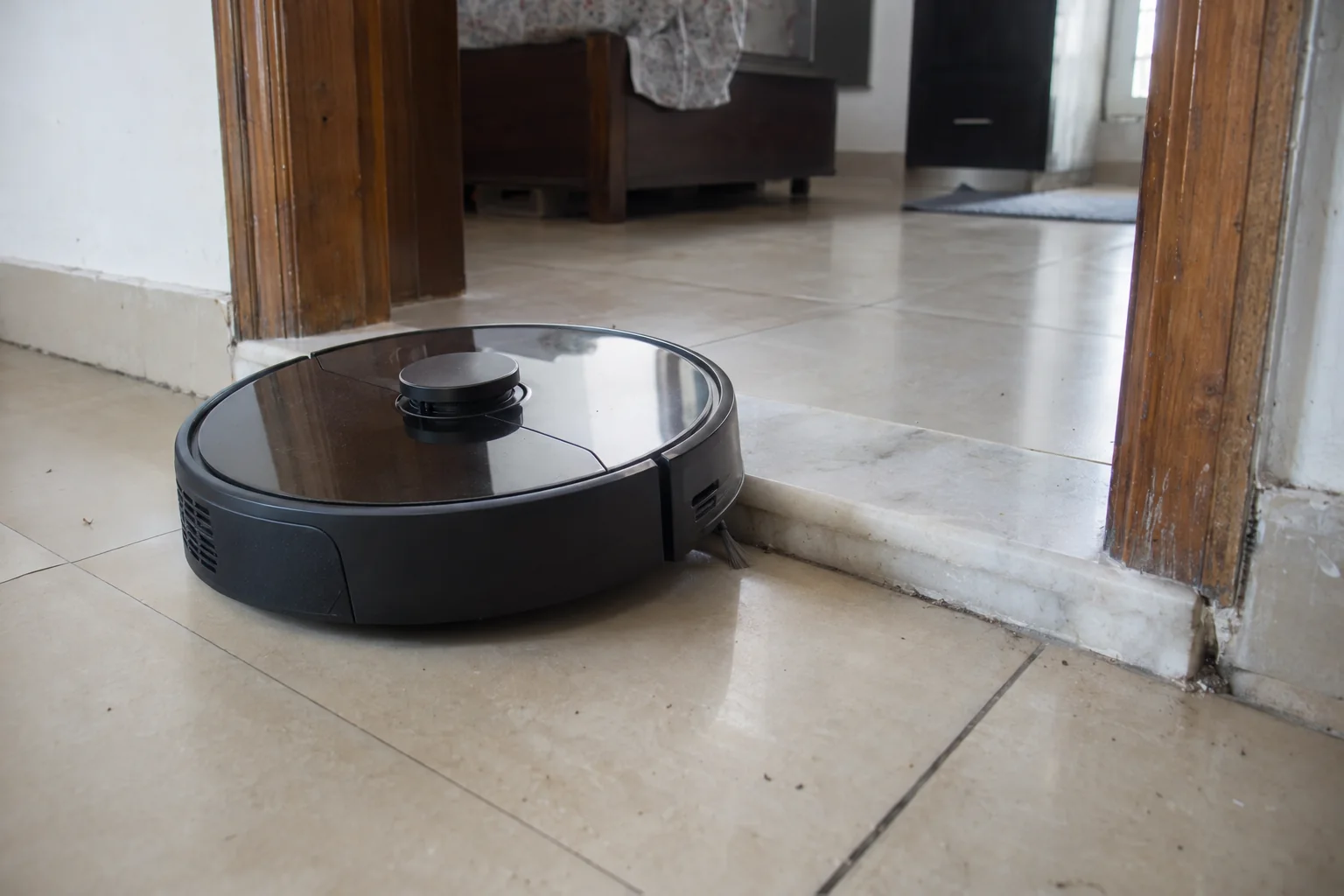 A robot vacuum stopped against a raised marble door threshold
